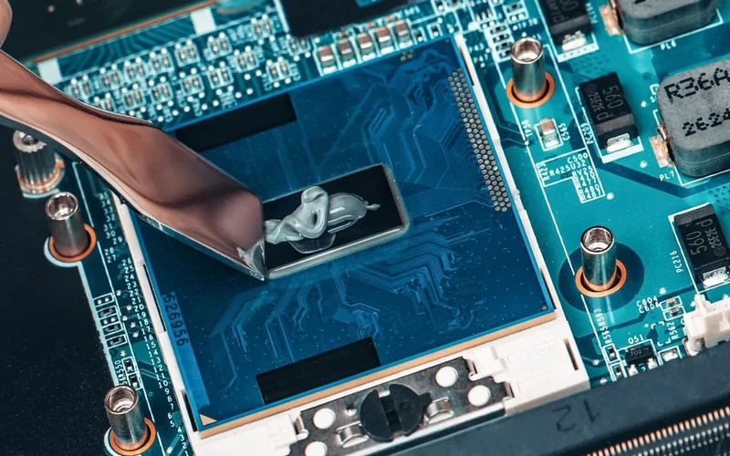 Technician applying thermal paste to a laptop CPU during repair